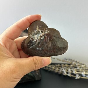 Op de afbeelding: Een donkerbruin, wolk-vormig kristal met een getextureerd, lichtgekleurd gebied. Het kristal wordt in een hand gehouden, met een vage achtergrond. Het kristal is een uniek decoratief item.