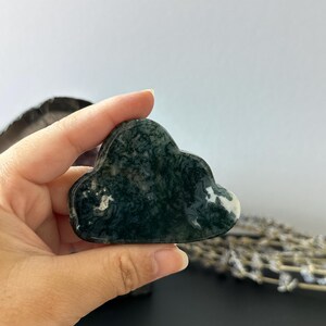 Könnte beinhalten: Eine handgehaltene, wolkenförmige Steinskulptur in Grün- und Weißtönen. Der Stein hat eine polierte, glänzende Oberfläche. Die Wolkenform ist ein dekoratives Element.