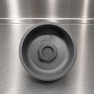 Pode incluir: Uma chave de filtro de &oacute;leo circular de metal cinza-escuro com acabamento exterior texturizado. O interior apresenta uma porca hexagonal central e o texto estampado 105/05. A ferramenta tem uma forma profunda de copo para manuten&ccedil;&atilde;o.