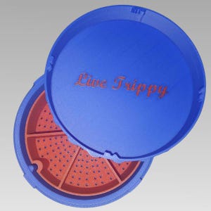 May include: A blue, circular container with a lid, featuring the text "Live Trippy" in orange. The interior is orange and divided into sections with small holes. The lid is partially open, revealing the inside.