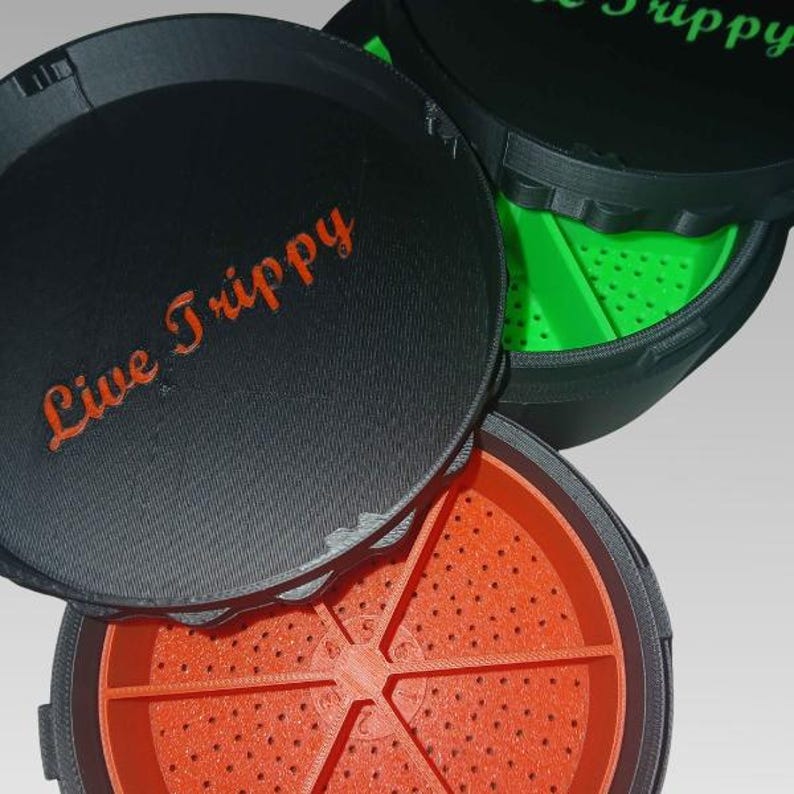 May include: Black and orange round container with the text "Live Trippy" in orange script. The container has a lid and a perforated orange interior. Another container is visible with a green interior.