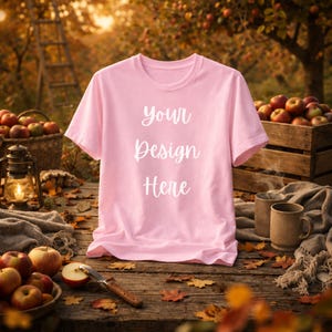 May include: A light pink short-sleeved t-shirt with the white text "your Design Here" printed on the front. The shirt features a crew neckline and is displayed as a flat garment, showcasing the fabric texture and the centered white lettering.