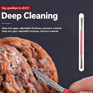 Könnte beinhalten: Ein dünnes, flexibles Reinigungswerkzeug mit einer metallisch geflochtenen Spitze und einem roten Griff, das die Spalten einer braunen Walnuss reinigt. Das Bild enthält den Text: Say goodbye to dirt!!! Deep Cleaning, Deep into gaps, adjustable thickness.