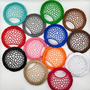 Peut inclure: Une collection de douze filets à cheveux circulaires de différentes couleurs, notamment turquoise, vert, marron, rouge, gris, bleu, rose, noir, orange, beige, blanc et rouge foncé. Chaque filet présente un motif en maille alvéolée.