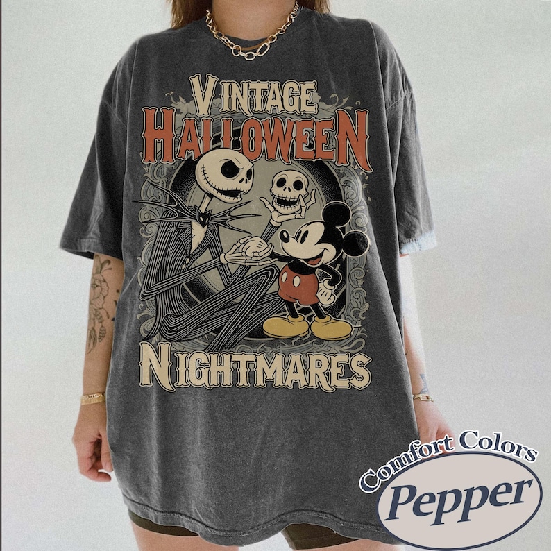 May include: A charcoal gray short-sleeve t-shirt featuring a graphic print with the text VINTAGE HALLOWEEN NIGHTMARES. The design depicts a tall skeletal figure holding a skull and a cartoon mouse character, set against an ornate circular frame.
