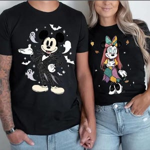 以下が含まれることがあります： ハロウィーンをテーマにした漫画のキャラクターが描かれた黒いTシャツ。1枚はコウモリ、幽霊、星とジャック・スケリントンが描かれています。もう1枚は、秋の葉と星が描かれたパッチワークドレスを着たミニーマウスが描かれています。