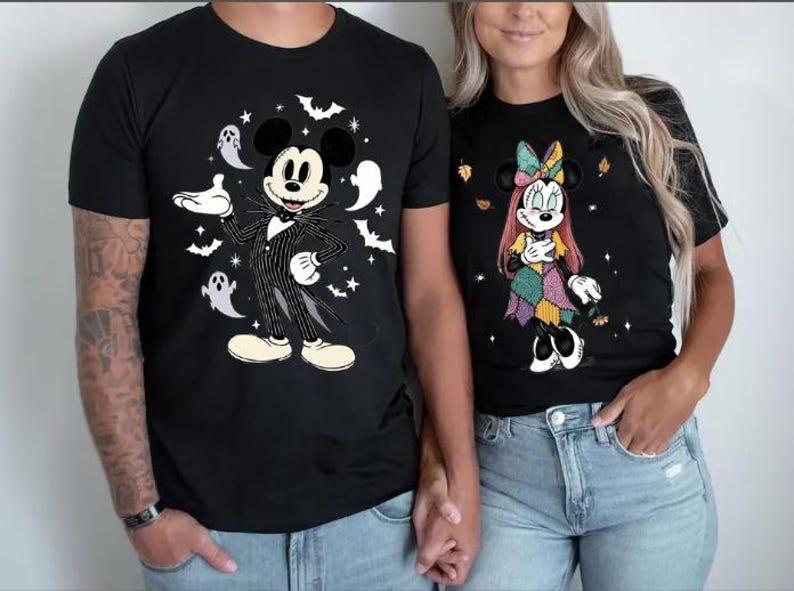 以下が含まれることがあります： ハロウィーンをテーマにした漫画のキャラクターが描かれた黒いTシャツ。1枚はコウモリ、幽霊、星とジャック・スケリントンが描かれています。もう1枚は、秋の葉と星が描かれたパッチワークドレスを着たミニーマウスが描かれています。