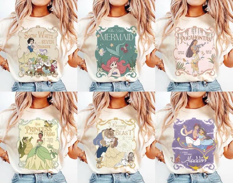 May include: Cream-colored t-shirts featuring various Disney princess designs. Each shirt showcases a different princess, including Snow White, Ariel, Pocahontas, Tiana, Belle, and Jasmine, with their respective movie titles. The designs are in a vintage, storybook style.