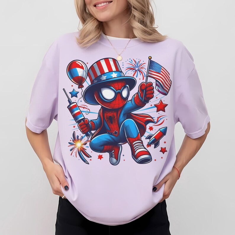 K&ouml;nnte beinhalten: Helllila T-Shirt mit einer Cartoon-Figur von Spider-Man in einem patriotischen Outfit, die eine US-Flagge und Feuerwerk h&auml;lt. Das Design umfasst ein rot-wei&szlig;-blaues Farbschema mit Sternen, Raketen und einem Ballon.