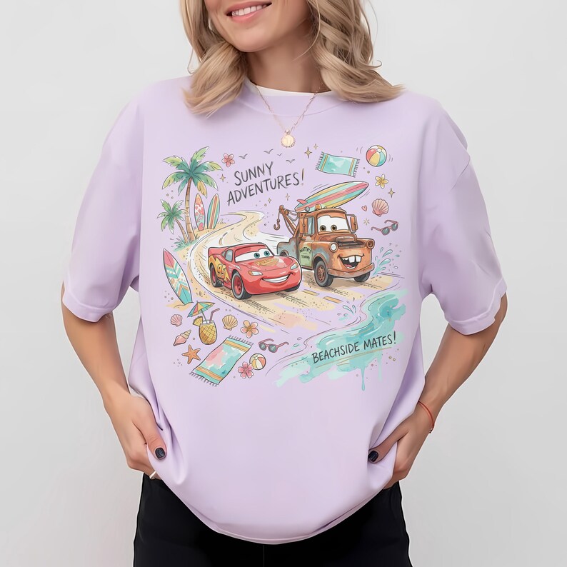 May include: A light purple t-shirt featuring a colorful graphic of Lightning McQueen and Mater from the movie Cars driving on a beach road. The design includes palm trees, surfboards, beach towels, and the text Sunny Adventures and Beachside Mates.