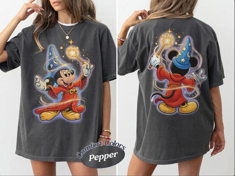 May include: Dark grey t-shirt with a front and back print of Mickey Mouse as a sorcerer, wearing a blue hat and red robe, holding a wand. The shirt has a distressed appearance and the text "Comfort Colors Pepper" is printed on the bottom.
