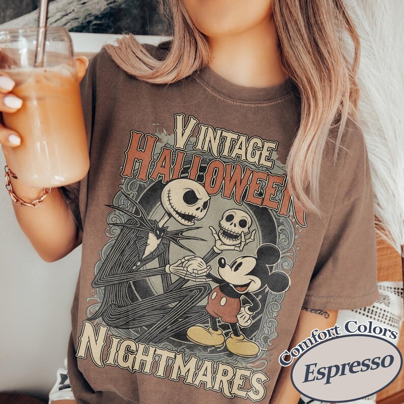May include: A brown t-shirt featuring a graphic print with the text VINTAGE HALLOWEEN NIGHTMARES. The design depicts a skeletal figure in a pinstripe suit holding a small skull, standing next to a cartoon mouse character in red shorts and yellow shoes.