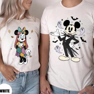 以下が含まれることがあります： ディズニーキャラクターが描かれた白いTシャツ。1枚はパッチワークのドレスを着たミニーマウス、もう1枚はコウモリと幽霊に囲まれたジャック・スケリントンに扮したミッキーマウス。下部には「WHITE」の文字。