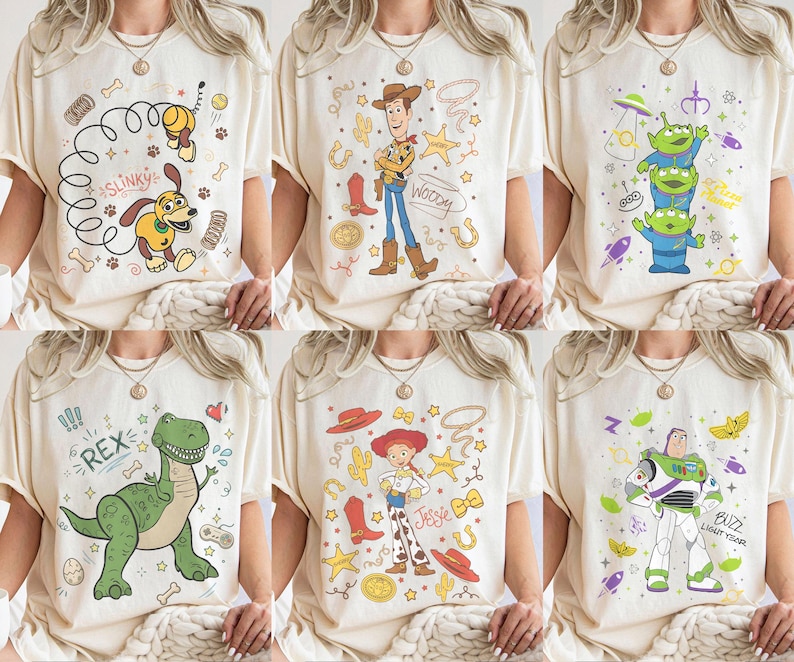 May include: Six cream-colored t-shirts featuring cartoon characters from the Toy Story franchise. Designs include Slinky Dog, Woody, the Aliens, Rex, Jessie, and Buzz Lightyear. Each shirt has a unique graphic with vibrant colors and character details.