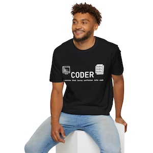 May include: Black t-shirt featuring the word "CODER" in white, accompanied by a computer monitor icon and binary code. The text "a machine that turns caffeine into code" is below the word "CODER".