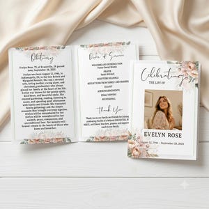 May include: A folded funeral program featuring a floral border with soft pink and peach flowers. The front cover displays the text Celebrating the life of Evelyn Rose, a photograph of a woman, and dates. The interior contains an obituary and order of service.