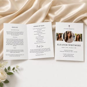 May include: A white folded funeral programme for Eleanor Whitmore featuring a cross, three circular portrait photos, and black text detailing the obituary, order of mass, and service information for the Catholic funeral mass held in Springfield, Illinois.