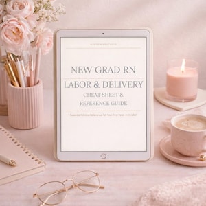 May include: A digital tablet displays the text "NEW GRAD RN LABOR & DELIVERY CHEAT SHEET & REFERENCE GUIDE." The image includes a pink candle, a cup of coffee, a notepad, pens, and glasses, all arranged on a pink surface.