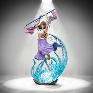 May include: A collectible figurine of a character with brown hair, wearing a white top and a purple skirt with pink floral patterns, holding a blue staff above the head. The figure is surrounded by a translucent blue water-like base effect.