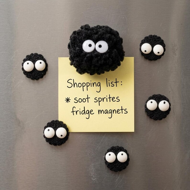 May include: Six black crocheted soot sprite fridge magnets with white plastic googly eyes. One larger fuzzy magnet holds a yellow square sticky note with the handwritten text: Shopping list: * soot sprites fridge magnets.