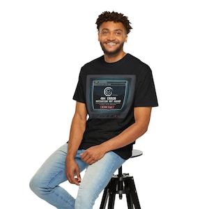 May include: Black t-shirt with a retro television screen graphic. The screen shows a "404 ERROR MOTIVATION NOT FOUND" message. The design includes a circular logo and the text "GO BACK TO MY". The shirt is worn by a person.
