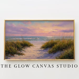 May include: A framed landscape painting depicts a beach scene at sunset. The artwork features a path through sand dunes leading to the ocean, under a sky of pink, purple, and orange hues. The text "THE GLOW CANVAS STUDIO" is at the bottom.