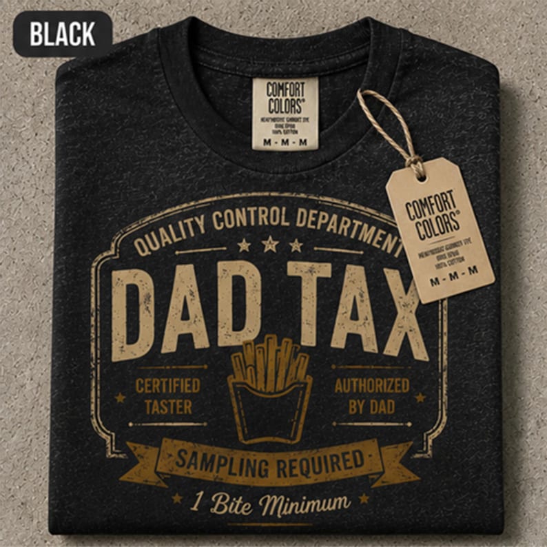 May include: A black short-sleeve t-shirt with a tan graphic print. The design features the text "DAD TAX" and "QUALITY CONTROL DEPARTMENT" with a french fry illustration. It includes the phrases "CERTIFIED TASTER," "AUTHORIZED BY DAD," "SAMPLING REQUIRED," and "1 Bite Minimum." A tan brand tag is attached.