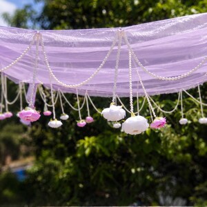 Lavendelfarbener Blumenkranz mit Perlenketten und Rosen | Floraler Brautbaldachin | Pastellfarbene Hochzeitskulisse | Dekoration für den Junggesellinnenabschied