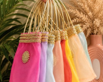 May include: A collection of small, rectangular drawstring pouches made of sheer, translucent fabric in various colors including hot pink, lavender, light blue, peach, red, yellow, and cream, each featuring gold metal ring handles.