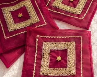 May include: Three square magenta organza pouches featuring a central gold metallic lace border in a square pattern. Each pouch is adorned with a small, six-pointed gold star embellishment centered within the lace frame, creating a decorative look.