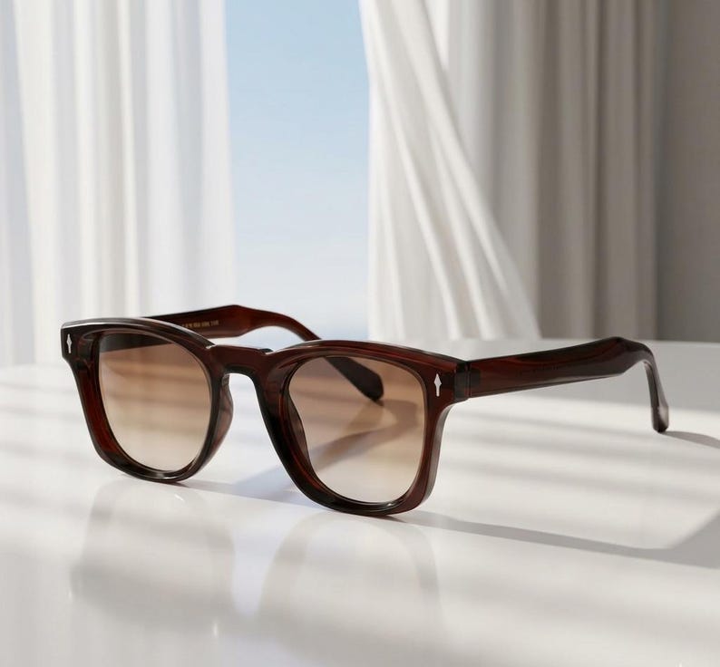 May include: Dark brown square sunglasses with gradient lenses. The frames have a small white arrow detail on the temples. The lenses transition from a darker brown at the top to a lighter brown at the bottom.