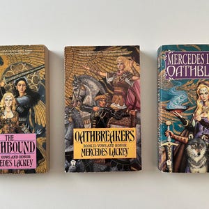Peut inclure: Trois romans fantastiques de Mercedes Lackey sont présentés. Les couvertures présentent des illustrations de femmes, d'épées et de créatures mythiques. Les titres incluent "The Oathbound", "Oathbreakers" et "Oathblood".