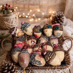 Puede incluir: Una colección de adornos decorativos de bellotas en una cesta tejida. Las bellotas presentan varios diseños, incluyendo patrones pintados, purpurina y adornos. Algunas tienen cintas rojas y blancas. El fondo incluye luces de hadas y una piña.