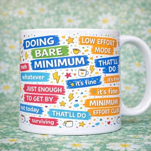 Puede incluir: Taza de cerámica blanca con frases coloridas como "Doing Bare Minimum", "Low Effort Mode" e "It's Fine". La taza tiene un asa blanca y está decorada con estrellas, tazas de café y rayos.