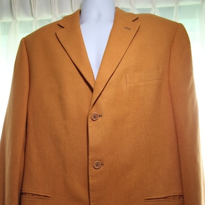 Puede incluir: Una chaqueta marrón con cierre de un solo botón y cuatro botones. La chaqueta tiene solapa de muesca y bolsillos de solapa.