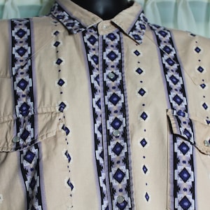 May include: A beige long-sleeved shirt with a geometric pattern in shades of purple, blue and black. The shirt has a button-down collar and two chest pockets.
