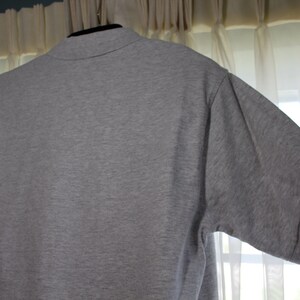 May include: A heather grey short-sleeved polo shirt with a collared neckline.