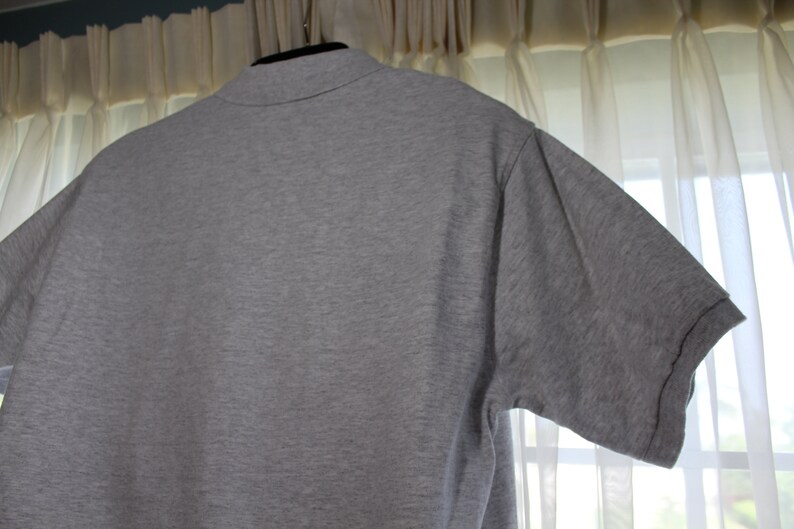 May include: A heather grey short-sleeved polo shirt with a collared neckline.