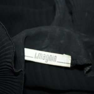 May include: Black pleated fabric with a white label that reads "L.Magnin".