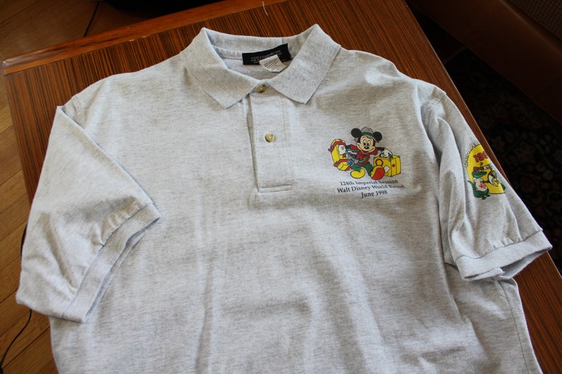 May include: Gray polo shirt with a Mickey Mouse graphic and the text "125th Anniversary Celebration Walt Disney World Resort June 1998".