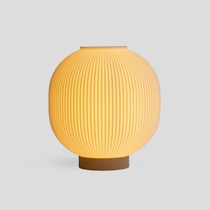 May include: A modern, spherical table lamp with a ribbed, off-white shade. The lamp sits on a brown, cylindrical base. The shade emits a warm, inviting glow, perfect for ambient lighting in a living room or bedroom.