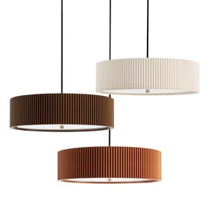 Peut inclure: Trois suspensions cylindriques à texture nervurée verticale, suspendues par de fins cordons noirs. Les abat-jours sont déclinés en crème, brun foncé et orange terre cuite, chacun doté d'une base circulaire plate avec une source lumineuse.