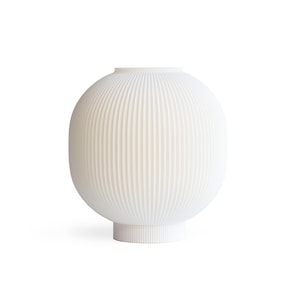 May include: A white, ribbed ceramic vase with a rounded body and a cylindrical base. The vase has a narrow opening at the top and a series of vertical ridges that run from top to bottom. The design is minimalist and modern.