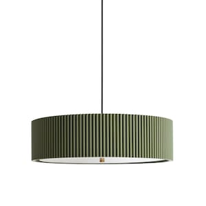 May include: A cylindrical pendant light fixture featuring a textured, olive green exterior with vertical ribbing. The lamp is suspended by a thin black cord and has a flat, circular white diffuser at the bottom with a small metallic center detail.