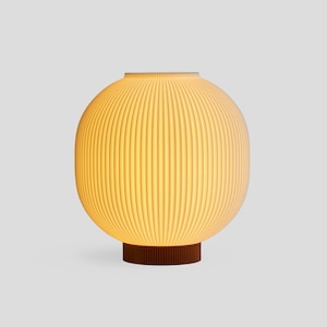 May include: A spherical table lamp with a ribbed, off-white shade. The lamp sits on a dark brown, cylindrical base. The lamp emits a warm, inviting glow, suggesting it is turned on. The design is modern and minimalist.