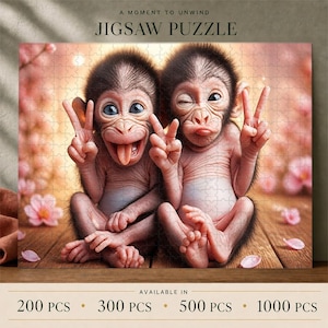 Könnte beinhalten: Ein Puzzle mit zwei Affenbabys auf einer Holzoberfläche mit rosa Blüten. Der linke Affe streckt die Zunge heraus, der rechte zwinkert. Beide zeigen das Friedenszeichen. Der Text lautet: A MOMENT TO UNWIND JIGSAW PUZZLE.