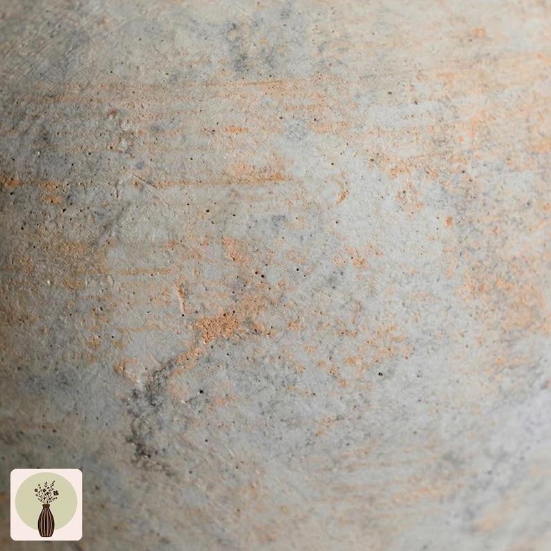 Puede incluir: Primer plano de una superficie texturizada, gris claro, con vetas de color naranja y marr&oacute;n. La superficie parece estar hecha de hormig&oacute;n o un material similar, con un aspecto rugoso y desgastado. La imagen es un primer plano, destacando los detalles de la textura.