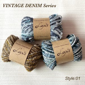 Puede incluir: Tres madejas de hilo Lapis de la serie Vintage Denim. El hilo es en tonos de azul, gris y marrón, con un aspecto texturizado. Cada madeja tiene una etiqueta marrón con el logotipo de Lapis y texto. La imagen también incluye el texto "Style: 01".