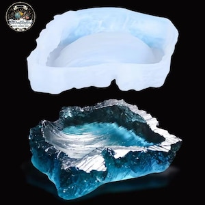 May include: A two-part image featuring a clear silicone mold and a finished resin piece. The mold is a light blue, irregular shape. The resin piece is a vibrant blue with silver accents, resembling a geode or a natural formation. The image is set against a black background.