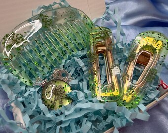 Set di accessori per capelli in resina verde, composto da pettine con fiori pressati, fermagli e collana con ciondolo.
